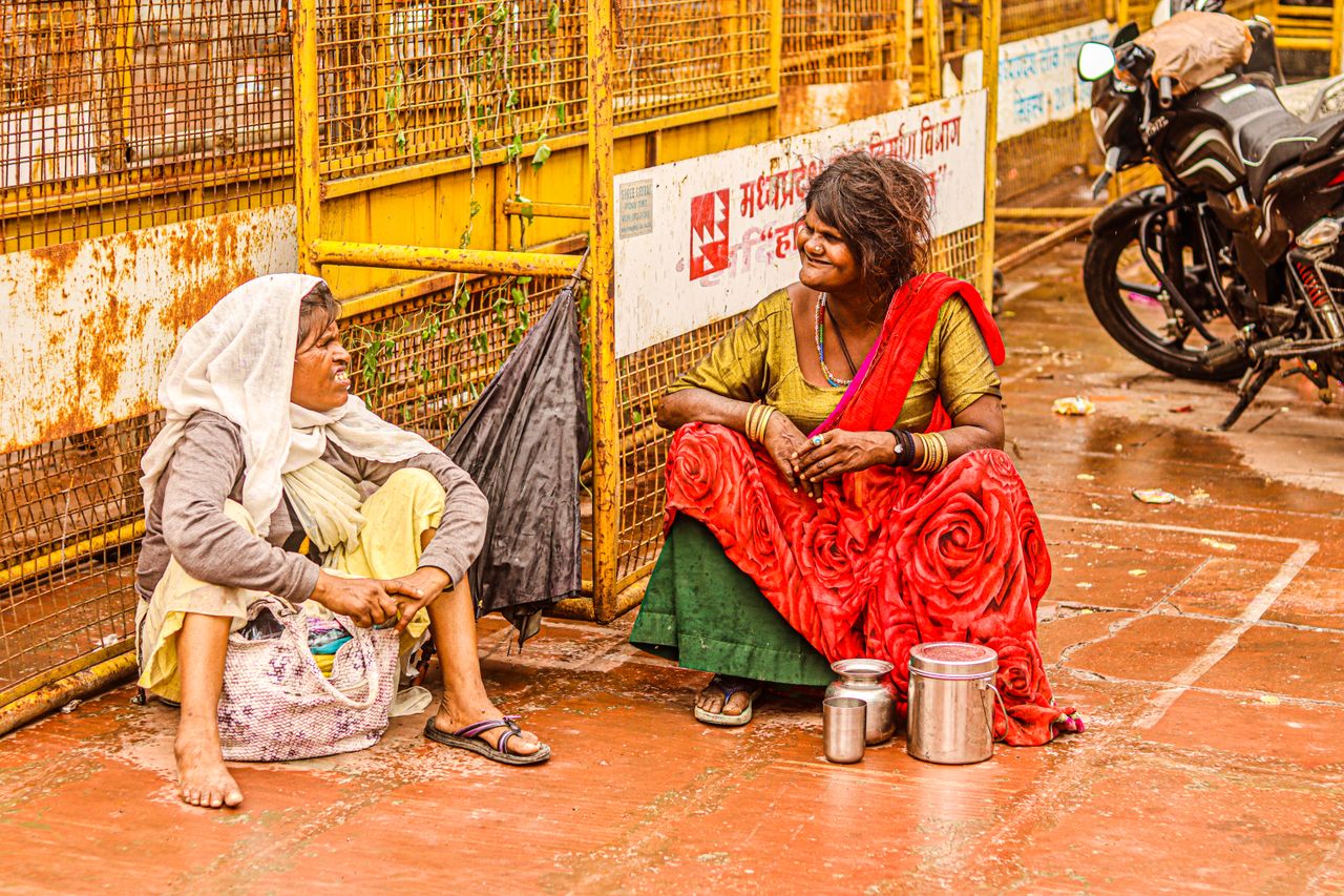 Two women in traditional attire sharing a moment on a bustling urban street.
